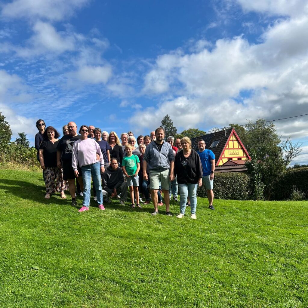 Das Bild zeigt den Gospelchor ProClaim aus Wuppertal auf einer grünen Wiese vor dem Heidehof in Hellenthal.